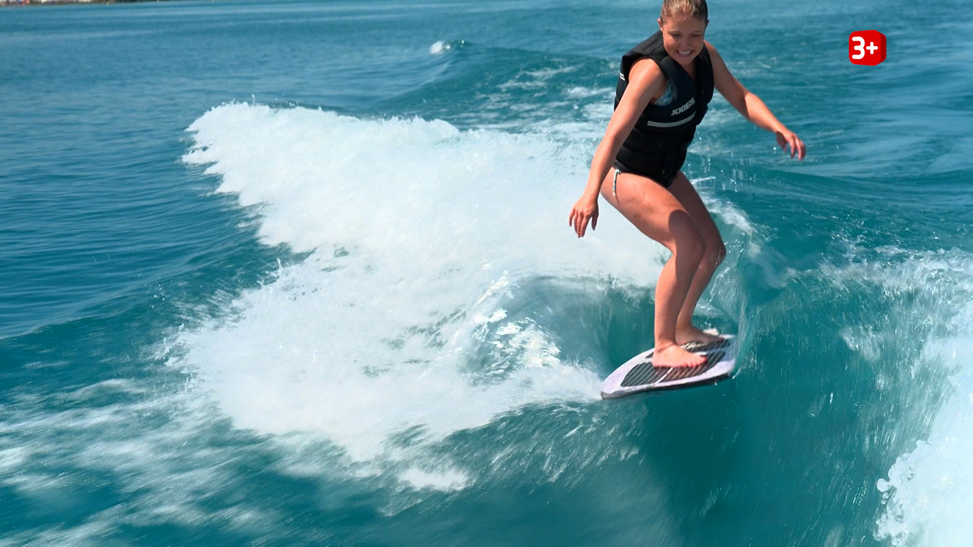 Surfer riding a wave on a blue ocean, wearing a life jacket and balance board rim.